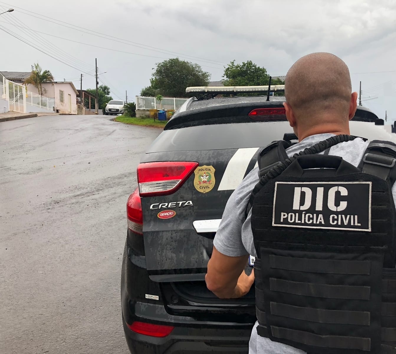 policial civil da DIC em frente a viatura e abrindo o porta-malas da mesma