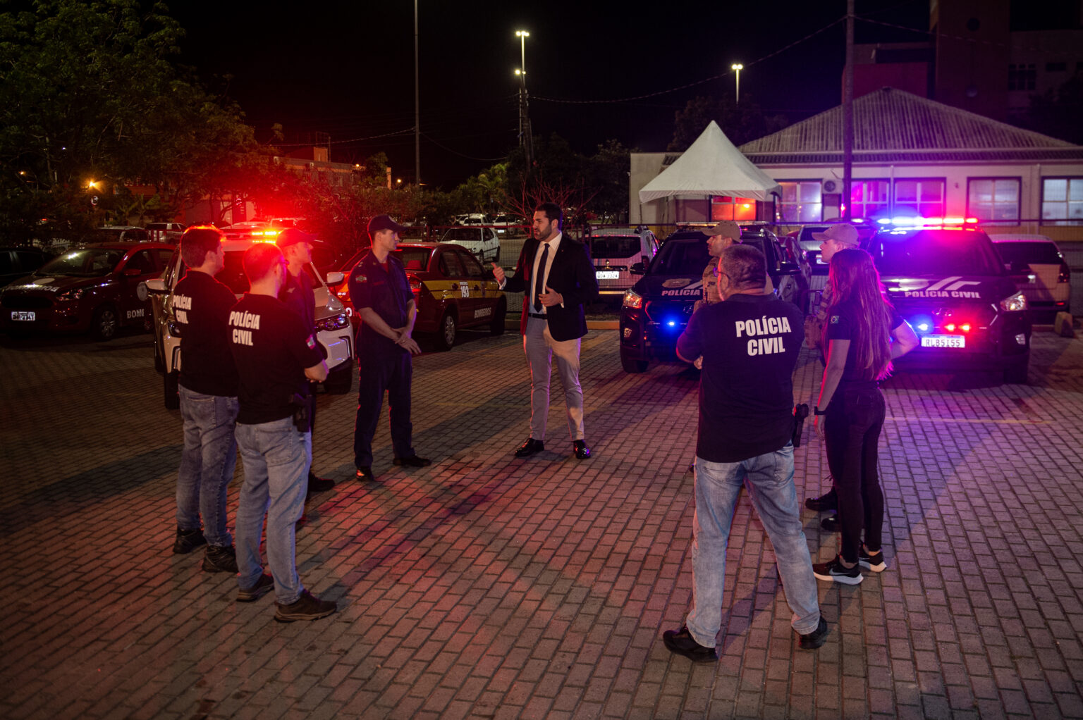 em frente das viaturas delegado Gustavo Kremer e policiais civis, militares e bombeiros dialogando