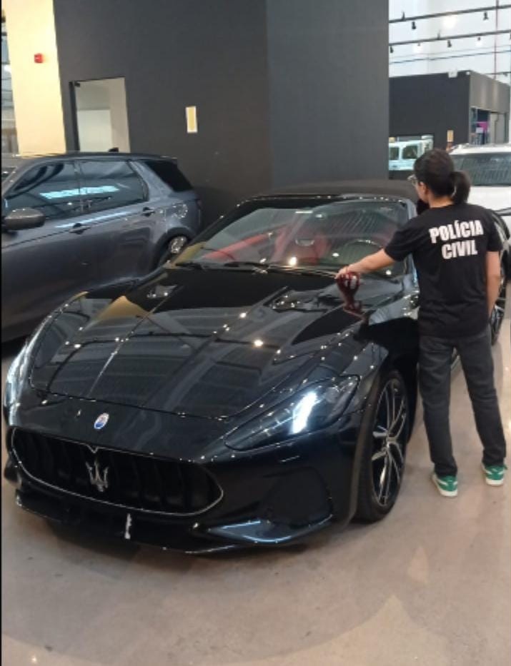 Policial civil em frente a um carro de luxo apreendido