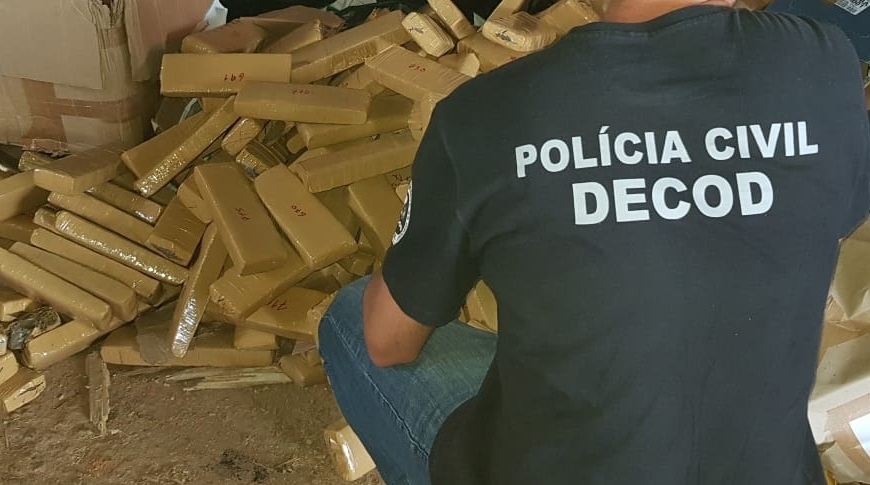 policial civil agachado envolta de 300 quilos de drogas em tablete