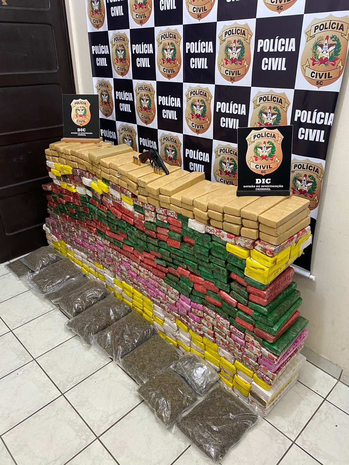 Drogas apreendidas com banner da PCSC ao fundo.