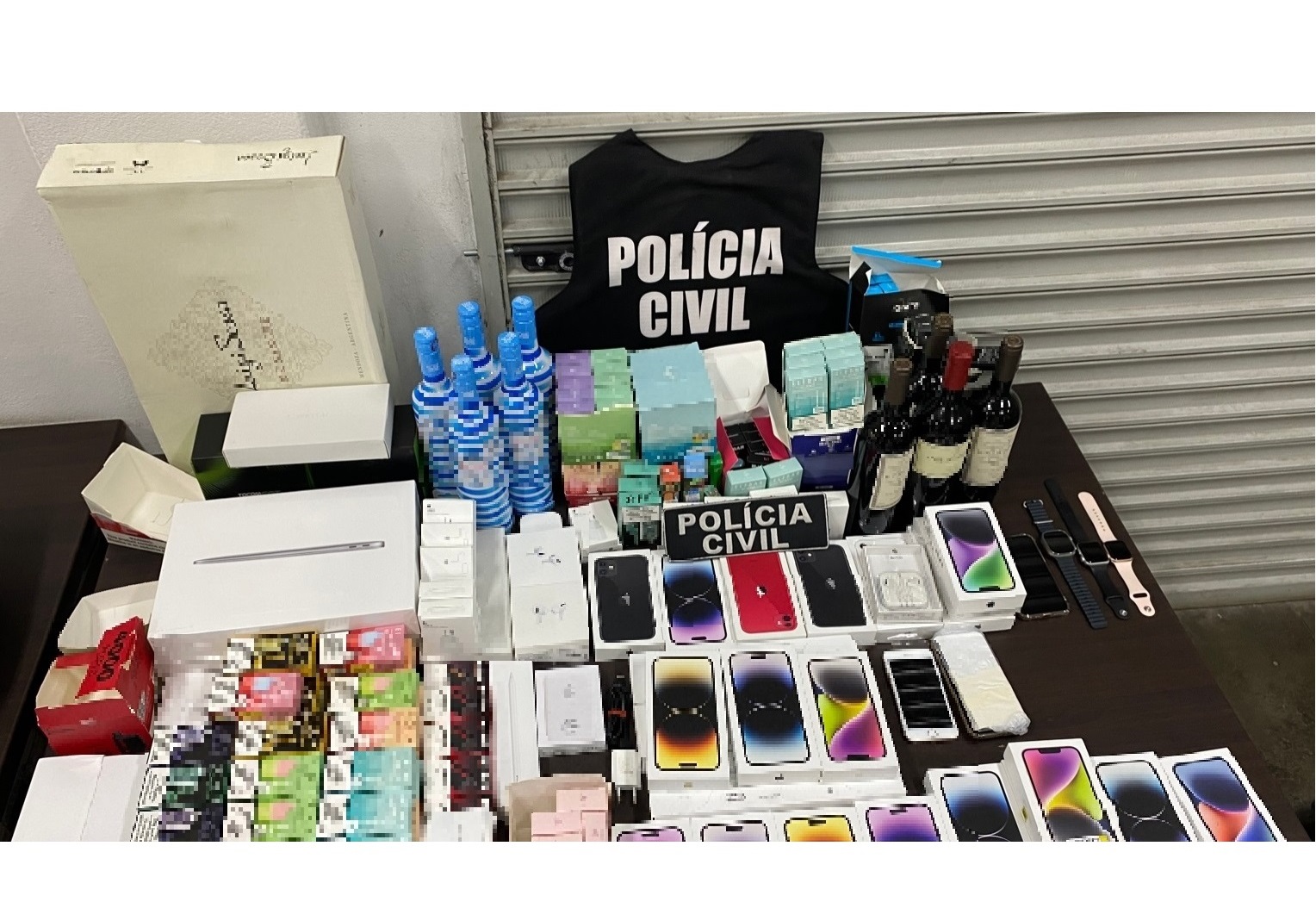 Colete da policia civil, celulares, vinhos e outros materiais sobre uma mesa