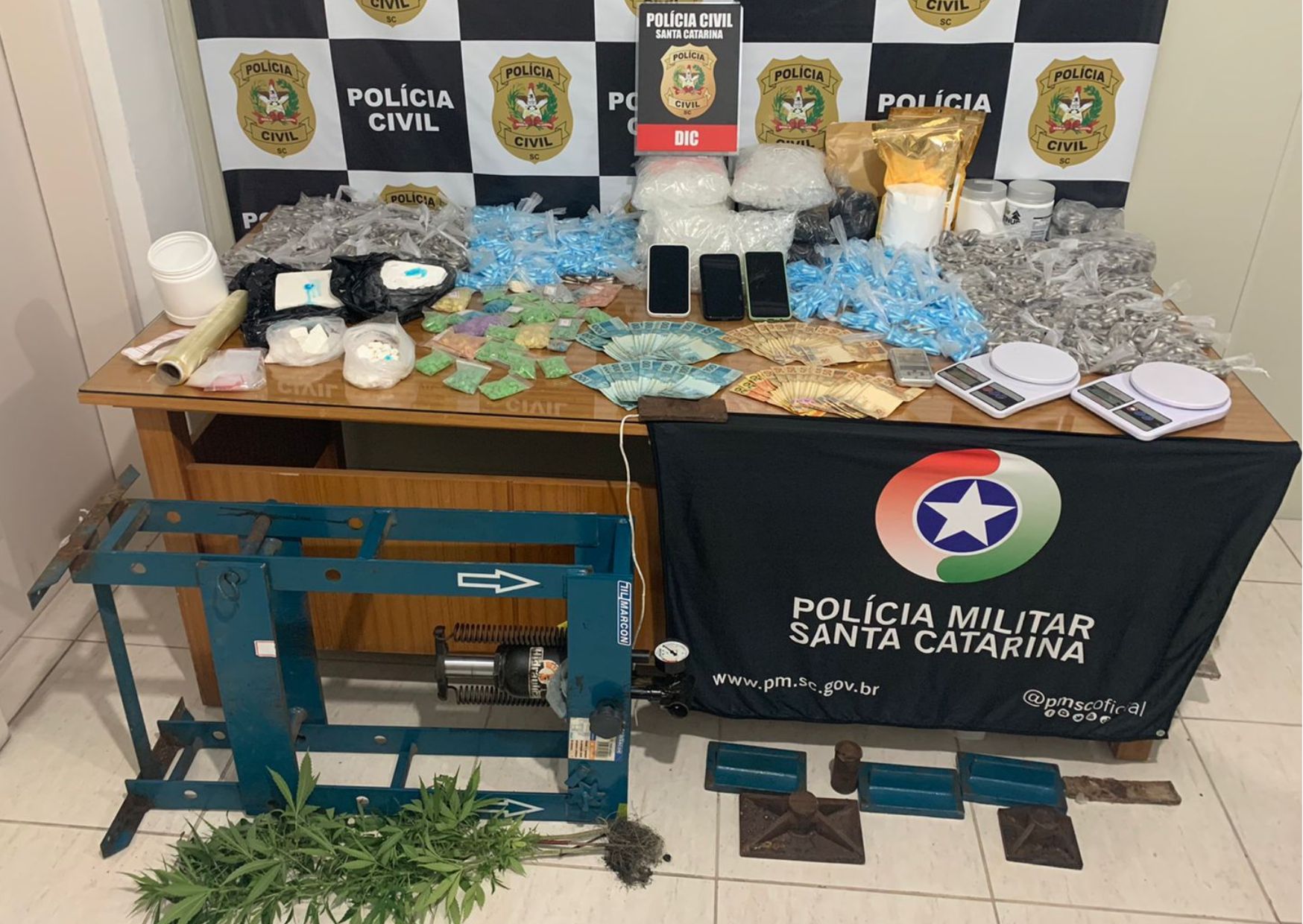 banner da policia civil e policia militar sobre a mesa drogas e dinheiro