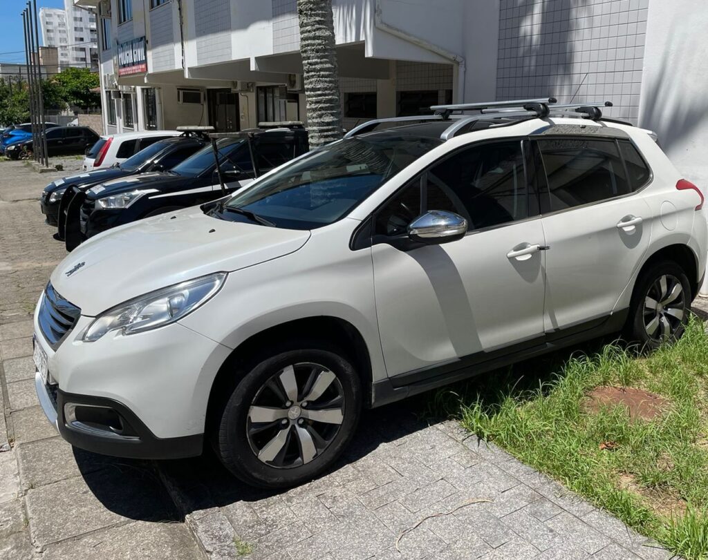carro recuperado no estacionado no estacionamento de uma delegacia ao lado de viaturas