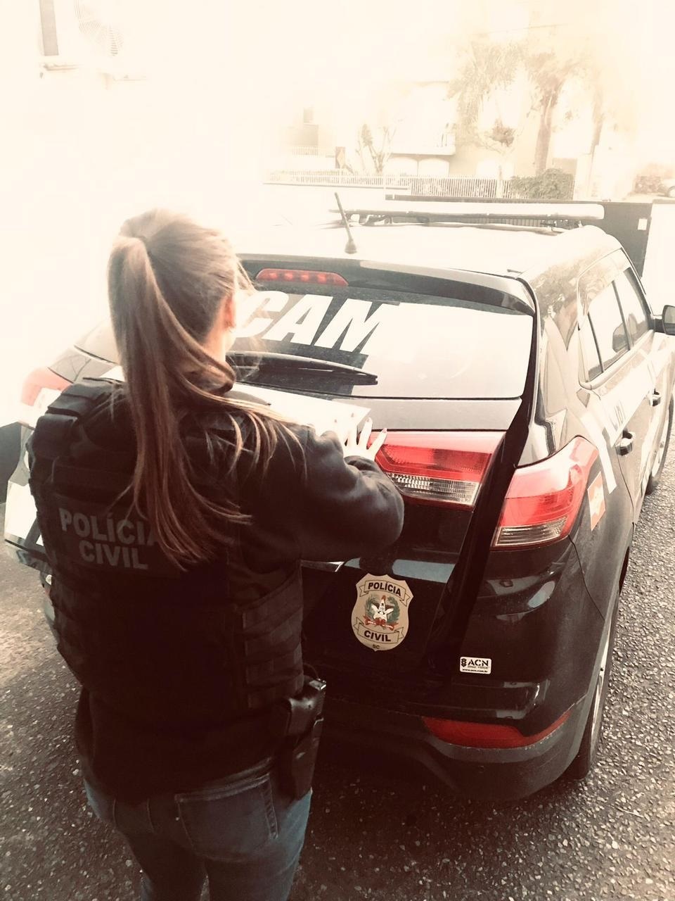 policial de costas em frente a viatura da DPCAMI