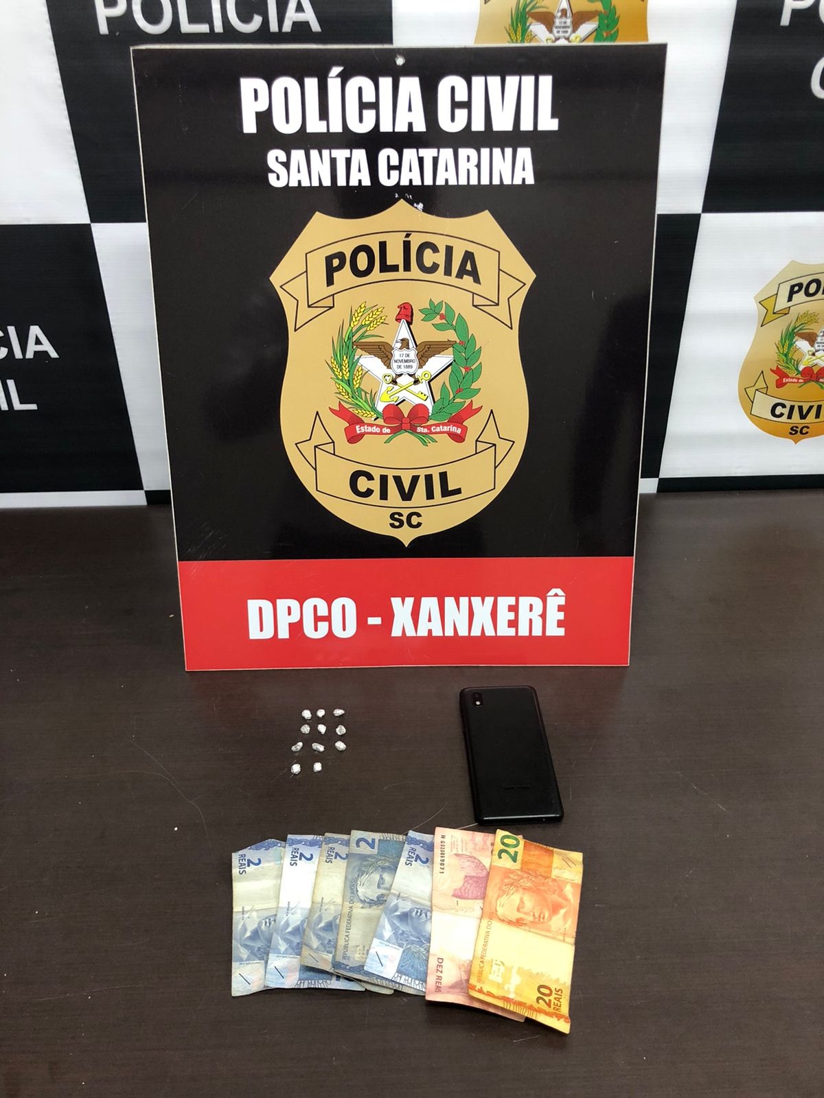 banner da pc/sc e a frente placa da DIC-XANXERE embaixo uma mesa com dinheiro recuperado