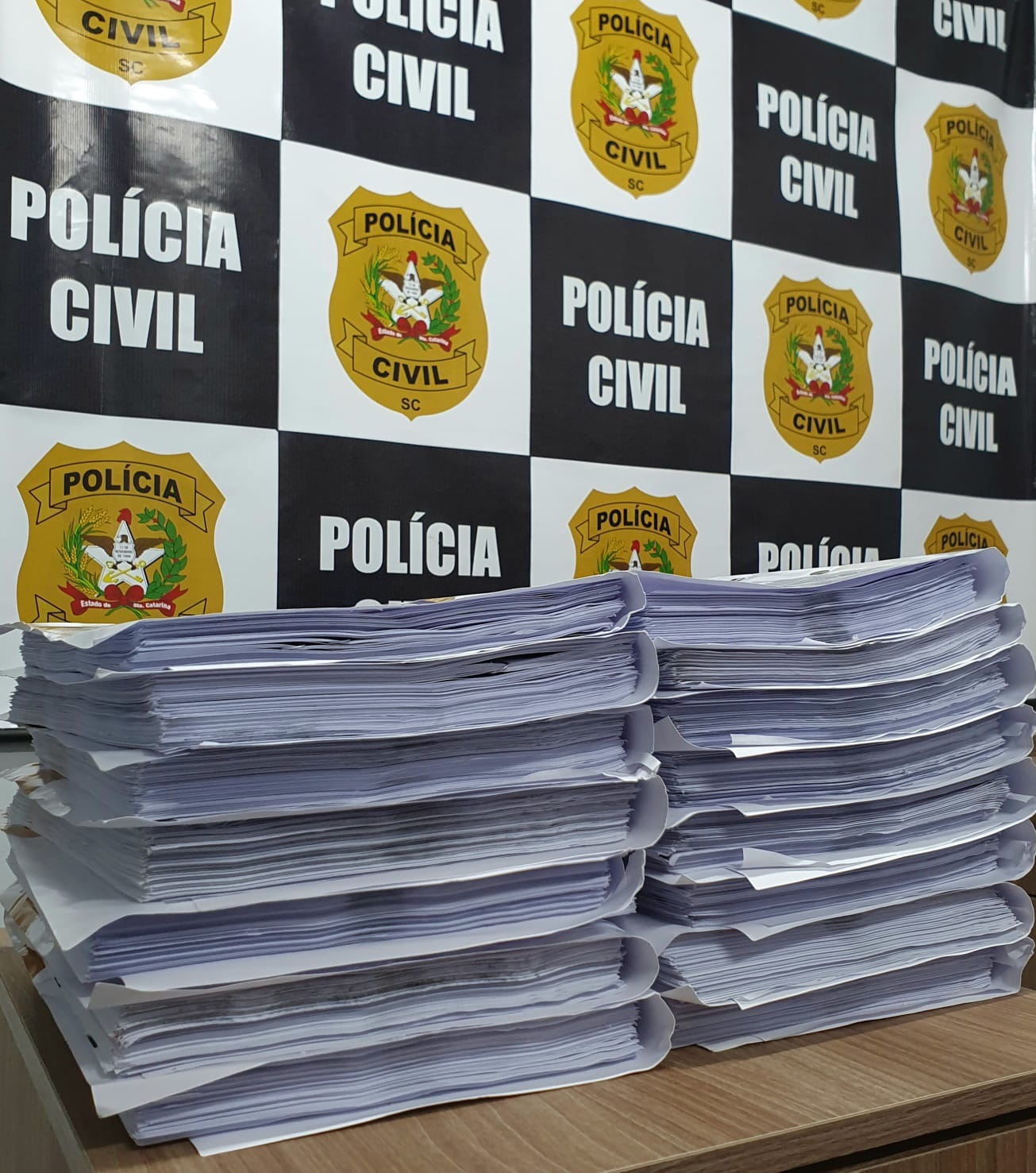 banner da pc no fundo e folhas sobre uma mesa a frente