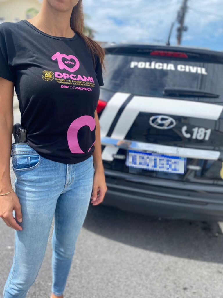 policial em frente a viatura com camiseta da DPCAMI 10 anos (DRP de Palhoça)