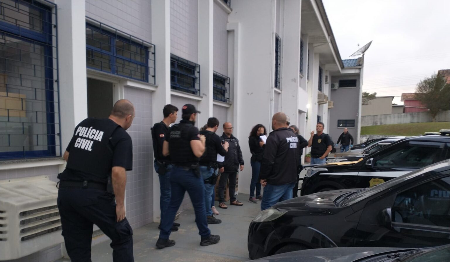 policiais civis ao lado de carros