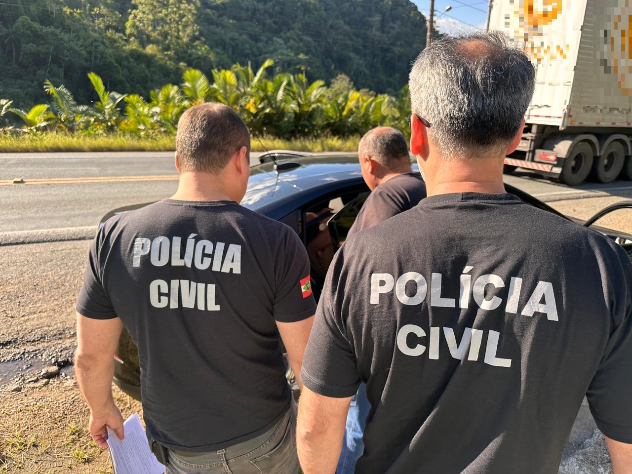 três policiais civis em frente a um carro semiaberto