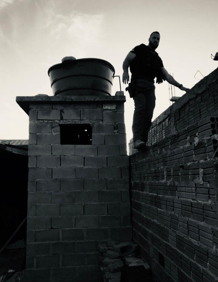 policial descendo um muro próximo a uma caixa de água