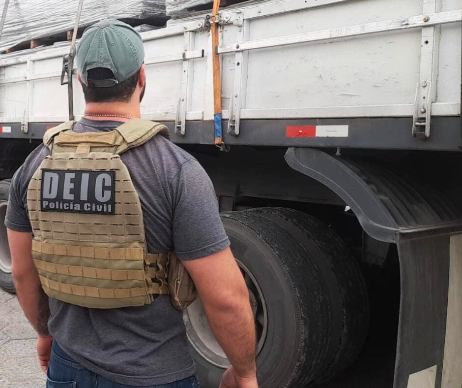 Policial Civil da DEIC em frente a um caminhão estacionado